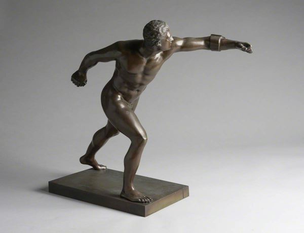 Photo of a bronze sculpture of a naked gladiator in action.